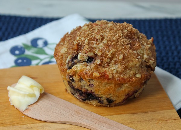 Blueberry muffin with butter on knife